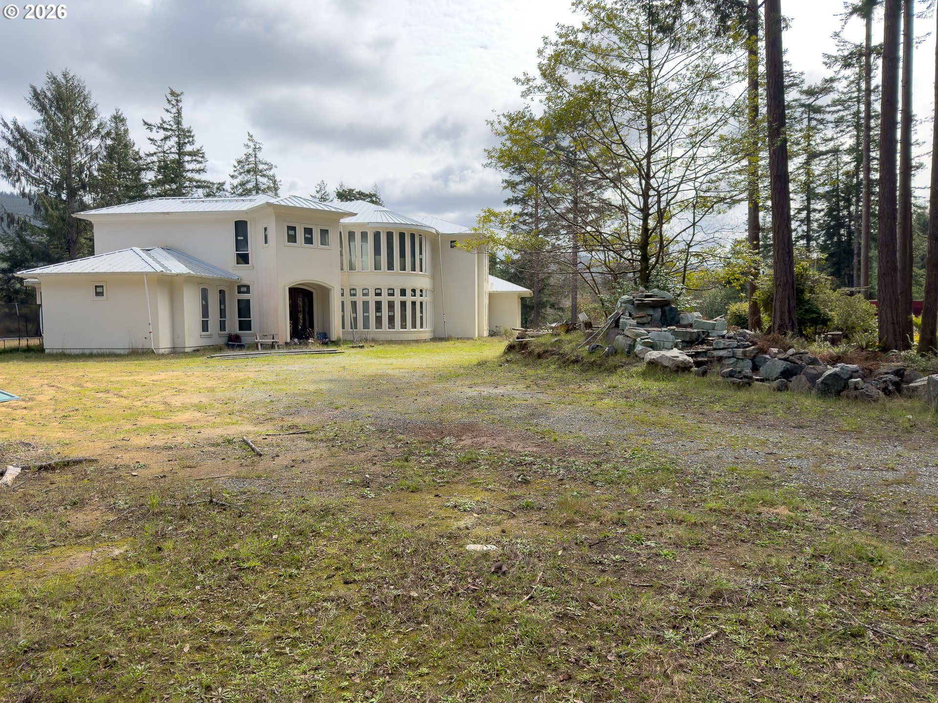 46914 Highway 101 Bandon, OR 97411 - Photo 36 of 48 a view of a big house with a big yard and large trees