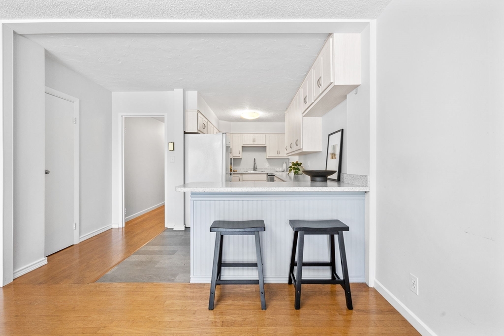 80 Park Street, Unit 23 Brookline, MA 02446 - Photo 19 of 38 a room with kitchen island a dining table chairs and a wooden floor