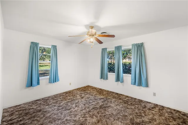 a view of a big room with windows and chandelier fan