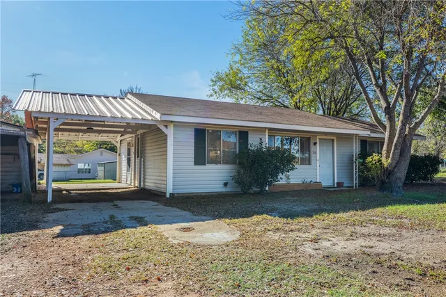 a view of a house with a yard and large tree