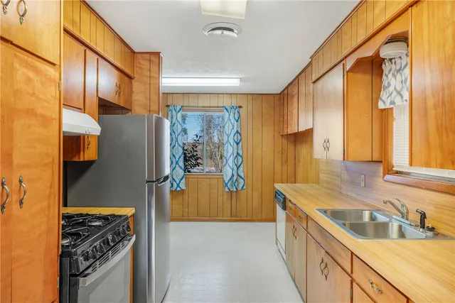 a kitchen with stainless steel appliances granite countertop a refrigerator a sink and a stove