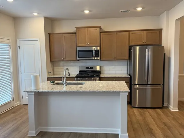 a kitchen with stainless steel appliances granite countertop a refrigerator a stove a sink and a microwave