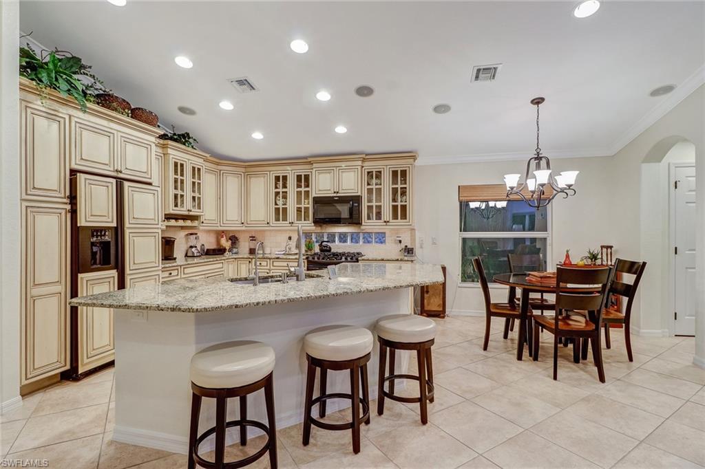 19731 Villa Rosa Loop Estero, FL 33967 - Photo 3 of 27 a kitchen with stainless steel appliances granite countertop a table chairs sink refrigerator and cabinets