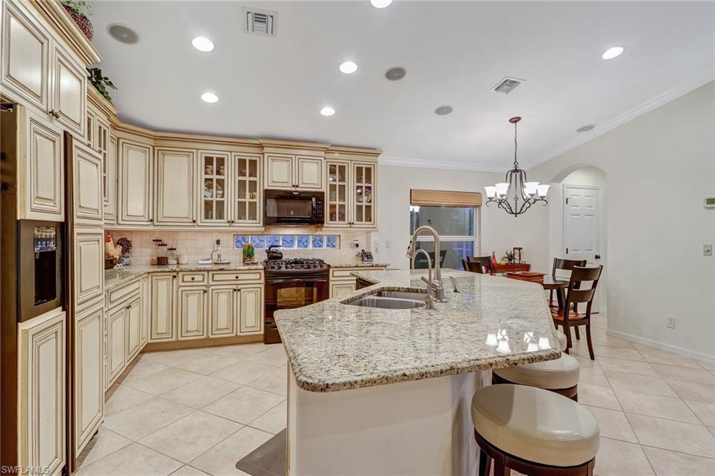 19731 Villa Rosa Loop Estero, FL 33967 - Photo 5 of 27 a kitchen with kitchen island granite countertop a stove a sink a refrigerator dining table and chairs