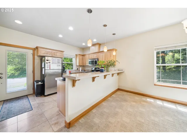 a kitchen with stainless steel appliances kitchen island granite countertop a refrigerator oven a sink with dishwasher and white cabinets next to a window