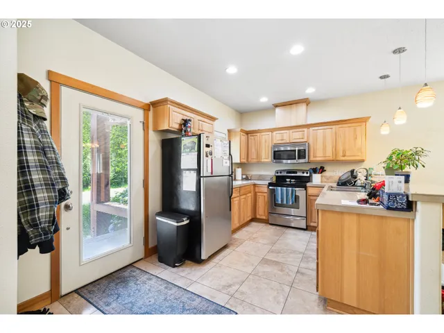 a kitchen with stainless steel appliances kitchen island granite countertop a refrigerator a stove top oven and a sink
