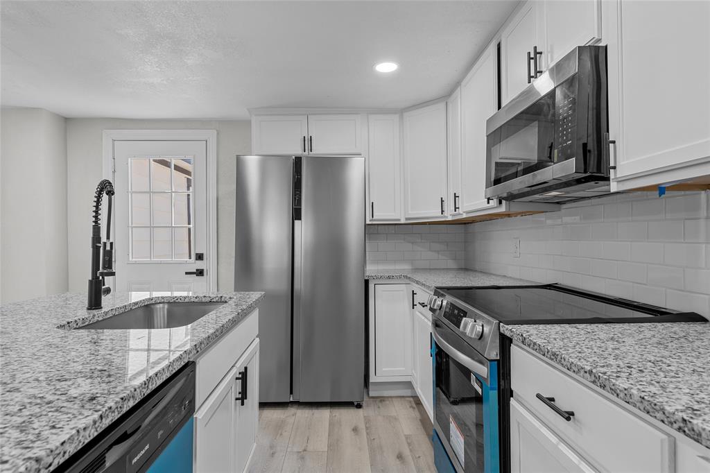 3530 Bluebird Street Bellmead, TX 76705 - Photo 11 of 24 a kitchen with stainless steel appliances granite countertop a sink stove and refrigerator