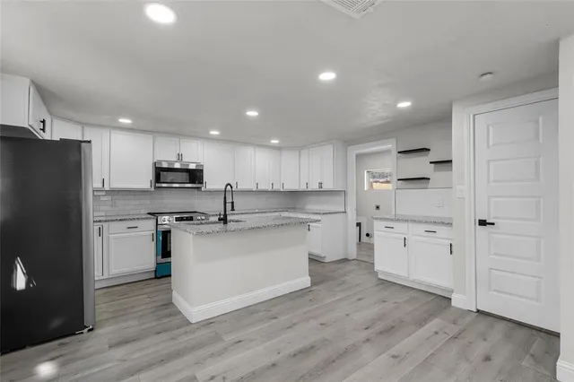 a kitchen with stainless steel appliances granite countertop a sink stove and refrigerator