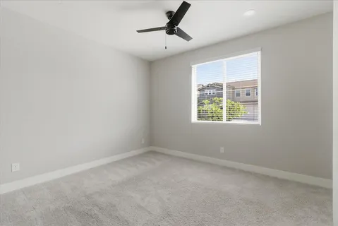an empty room with a window and a ceiling fan