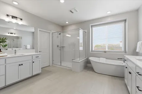 a spacious bathroom with a double vanity sink a large mirror and a bathtub