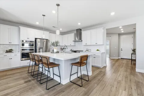 a kitchen with stainless steel appliances kitchen island granite countertop a wooden floor and white cabinets