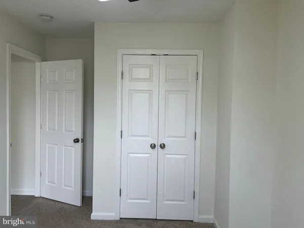 an empty room with chandelier fan and windows