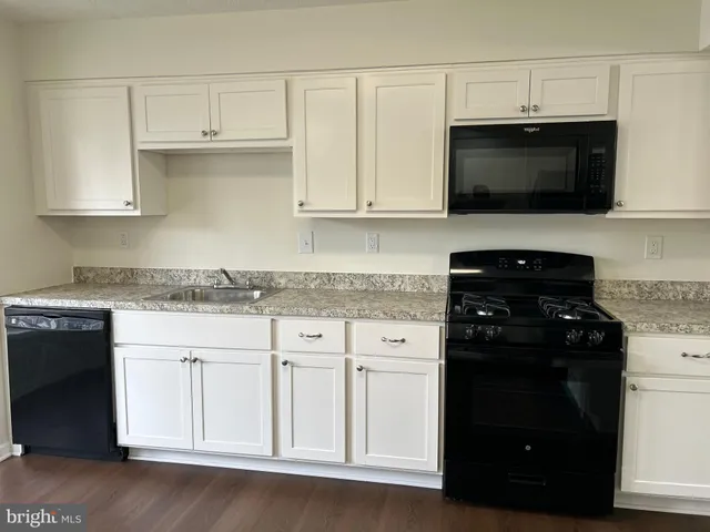 a kitchen with white cabinets and black appliances