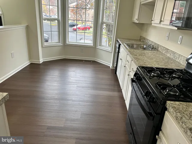 a kitchen with granite countertop a stove and a wooden floor