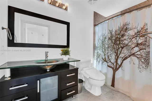 a bathroom with a granite countertop toilet sink and mirror