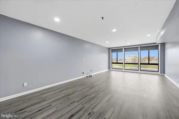a view of an empty room with wooden floor and fan