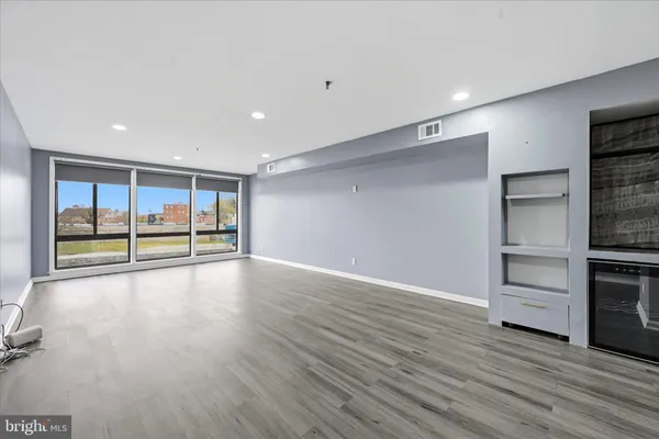 a view of an empty room with wooden floor and fence