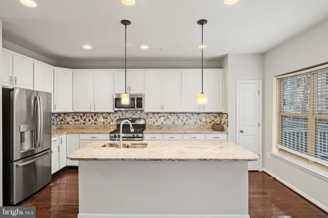 a kitchen with kitchen island granite countertop a sink a counter space appliances and cabinets