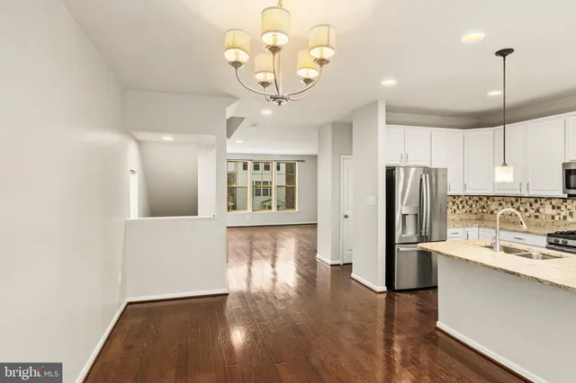 a kitchen with stainless steel appliances a refrigerator oven a sink dishwasher and a stove with wooden floor