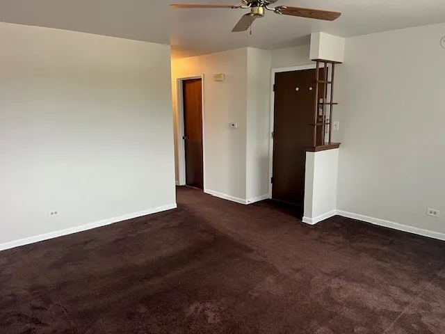 an empty room with a ceiling fan and closet area