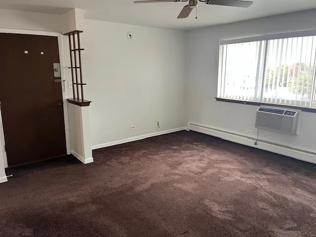 an empty room with windows and chandelier fan