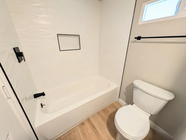 a white toilet sitting next to a bath tub