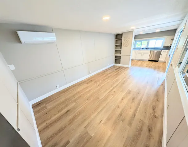 a view of an empty room with wooden floor and a window
