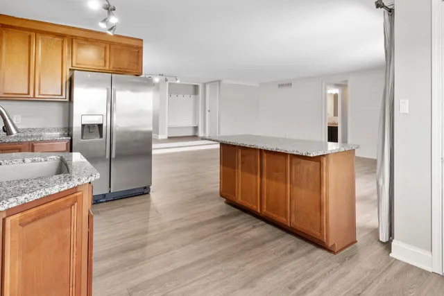 a kitchen with granite countertop a refrigerator a sink and wooden cabinets