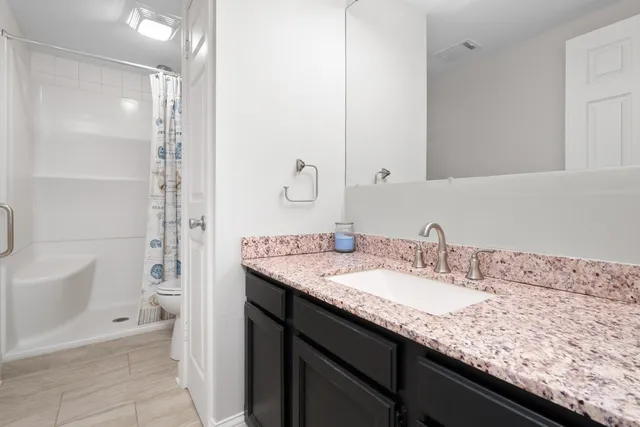 a bathroom with a granite countertop sink a mirror and a bathtub