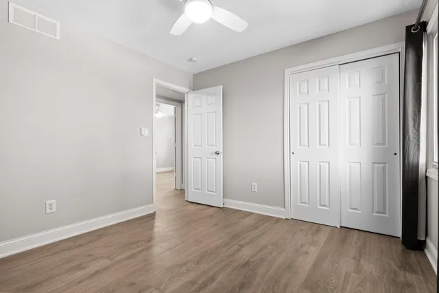 an empty room with wooden floor and windows