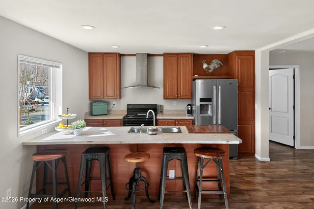 a kitchen with stainless steel appliances granite countertop a refrigerator a stove a sink a dining table and chairs