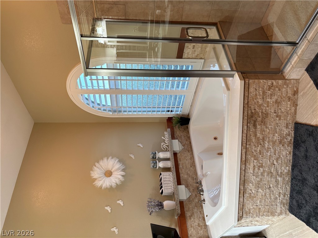 977 Rhyolite Terrace Henderson, NV 89011 - Photo 18 of 33 An arched window with built-in shutters illuminates the tiled soaking tub and adjacent glass shower.