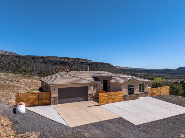62 North Lucky 7 Road Veyo, UT 84782 - Photo 37 of 43 View of front of property with stone siding, a mountain view, an attached garage, stucco siding, and a tile roof