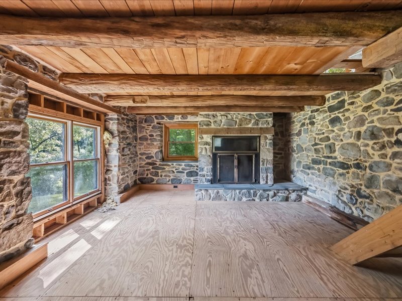 1168 Mt Pleasant Road Bangor, PA 18013 - Photo 90 of 100 Massive exposed beams and rugged stone walls frame a rustic room awaiting final floor finishes.