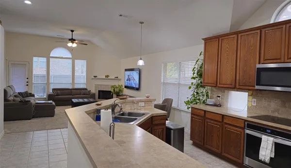 a kitchen with stainless steel appliances granite countertop a stove a sink dishwasher a dining table and chairs with wooden floor