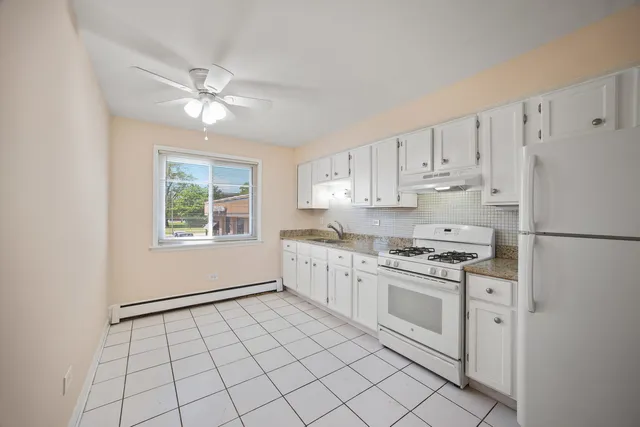 a kitchen with white cabinets appliances and a window