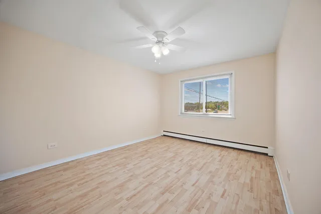 an empty room with wooden floor chandelier fan and windows