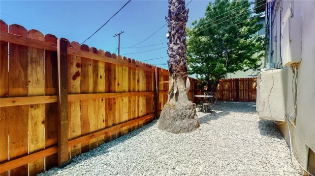 a view of a backyard with wooden fence and a large tree