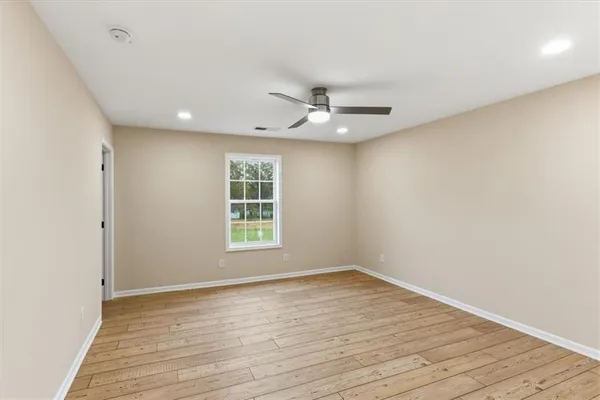 an empty room with wooden floor ceiling fan and windows