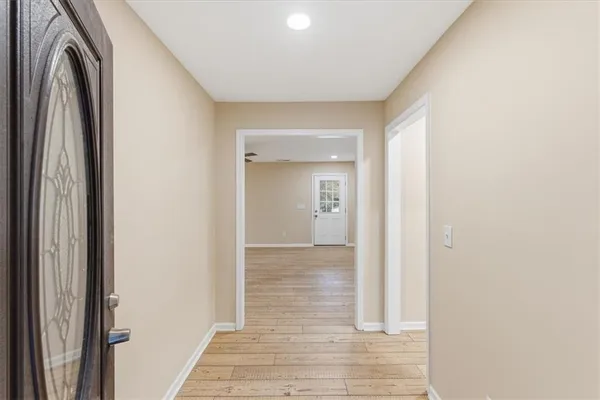a view of a hallway with wooden floor and a bathroom