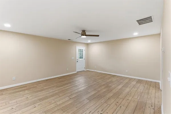 an empty room with wooden floor and windows