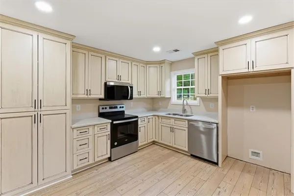 a kitchen with stainless steel appliances granite countertop a stove a sink and a refrigerator with wooden floors