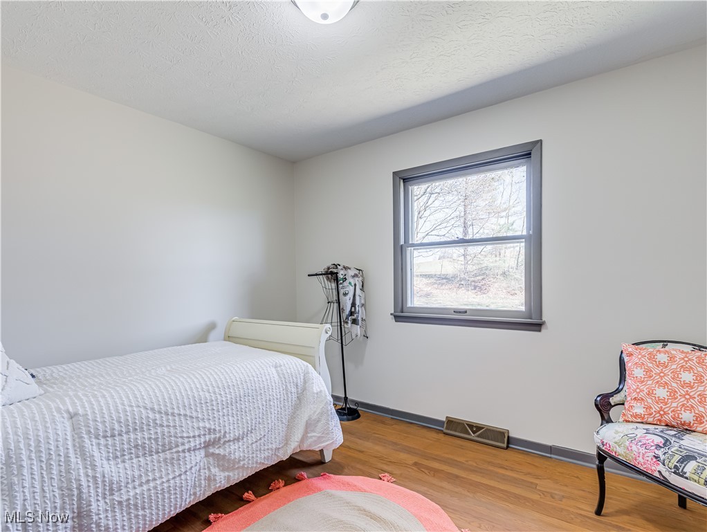3995 Cottage Grove Road Uniontown, OH 44685 - Photo 23 of 29 Bedroom with baseboards, a textured ceiling, visible vents, and wood finished floors