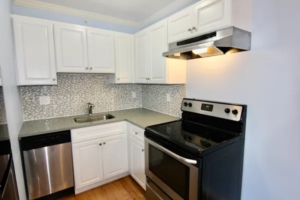a kitchen with stainless steel appliances granite countertop white cabinets and a stove top oven