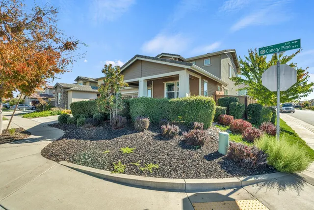 a front view of a house with a yard and potted plants
