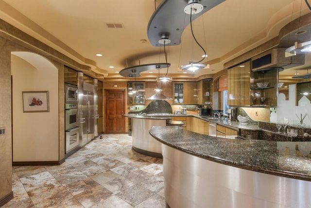 a kitchen with stainless steel appliances granite countertop a sink a stove and a refrigerator