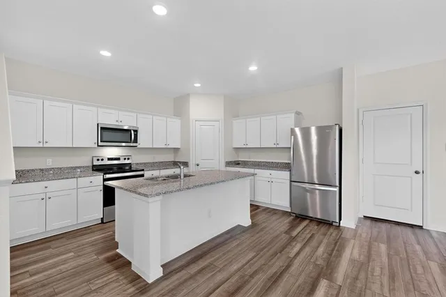a kitchen with stainless steel appliances a stove top oven a sink and a refrigerator