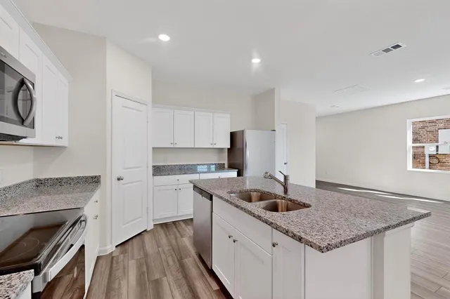 a kitchen with granite countertop a refrigerator stove a sink and dishwasher with wooden floor