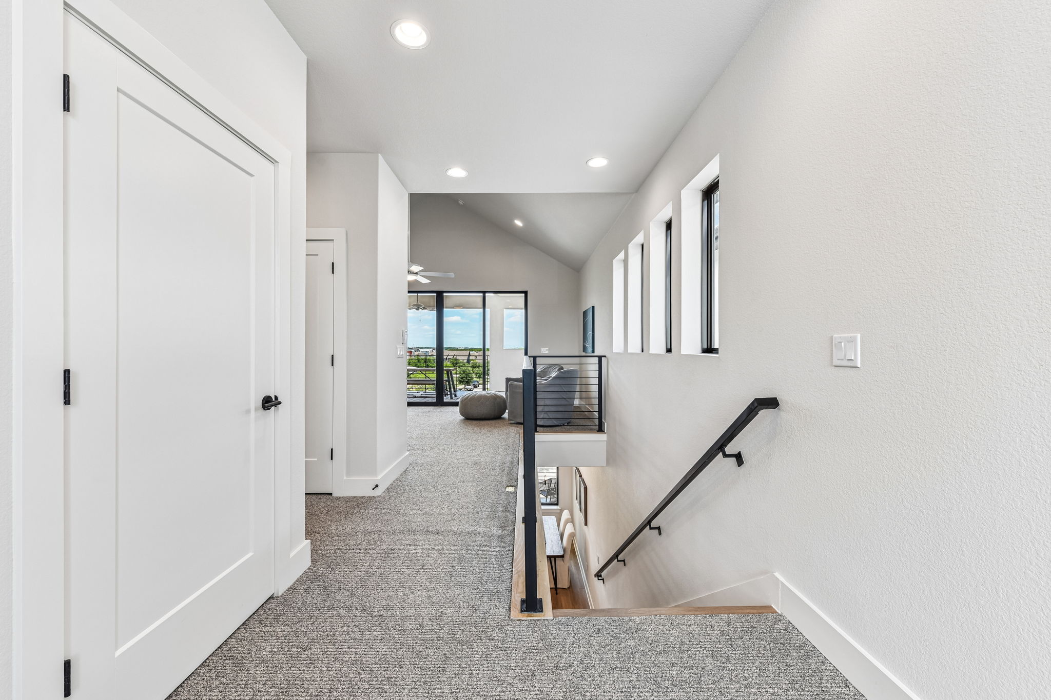9033 Cattle Baron Path Austin, TX 78747 - Photo 25 of 40 A well-lit landing and hallway lead to a bright living space with vaulted ceilings and outdoor access.