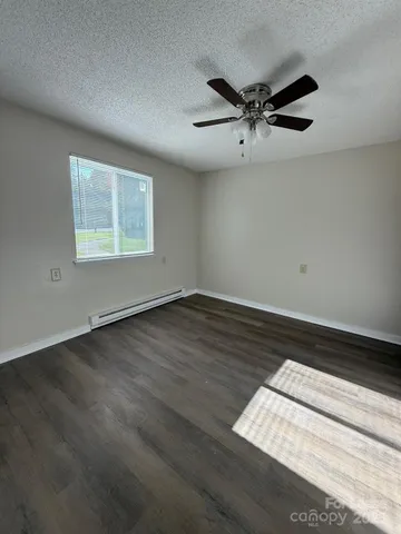 an empty room with wooden floor fan and windows